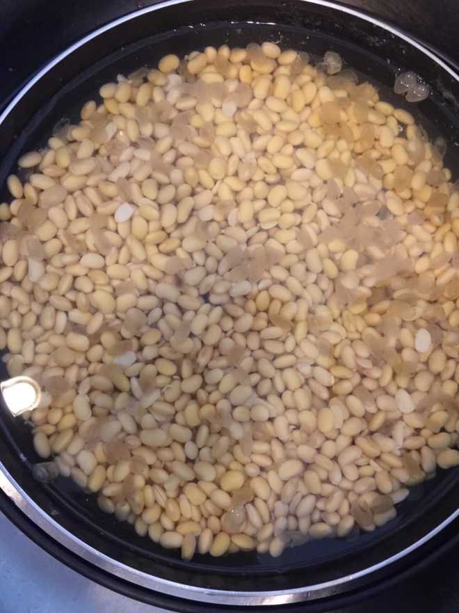 After soaking, wash well  with bare hands and scrub soy beans together to remove softened skin.  